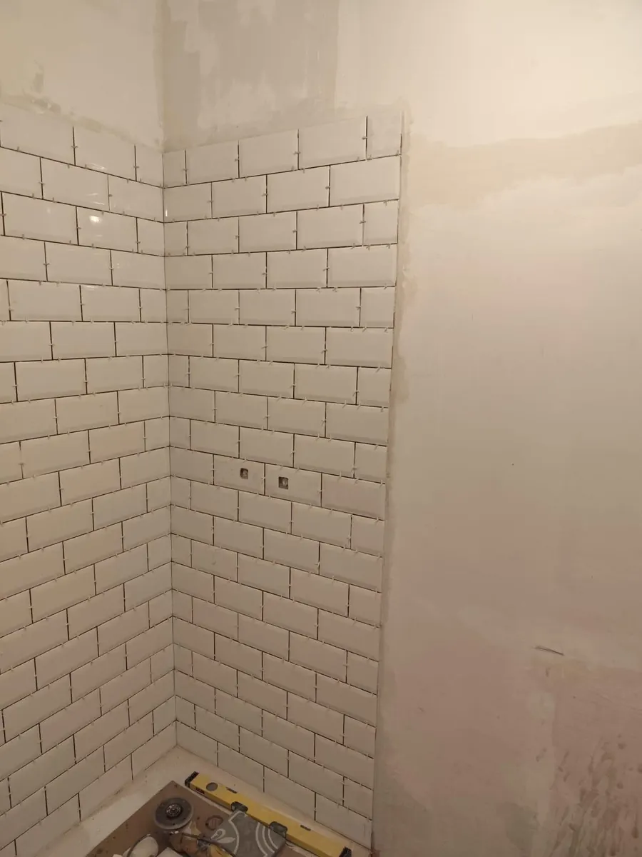 Pose de la faïence métro blanche dans la douche, en cours de chantier