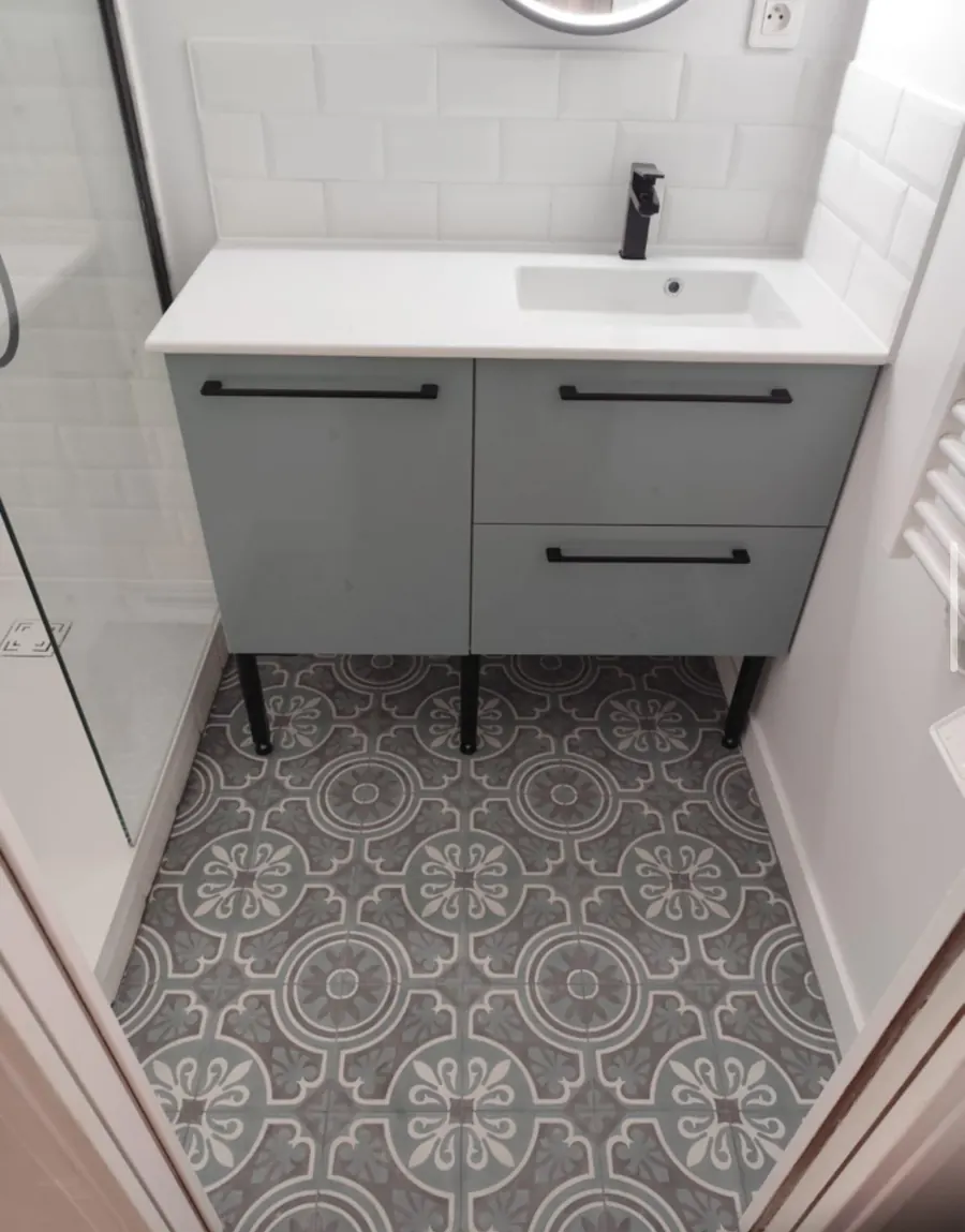 Salle de bain terminée : sol en carreaux effet ciment, meuble vasque gris-vert et robinetterie noire
